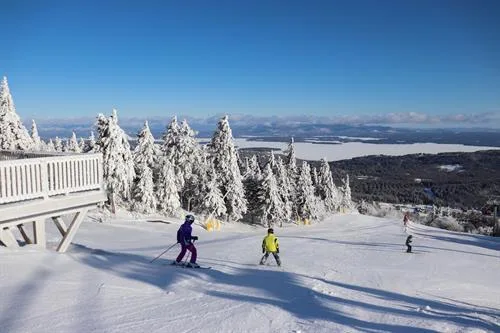 Skiers on an open trail at Gunstock Mountain Resort with Lake Winnipesaukee in the distance