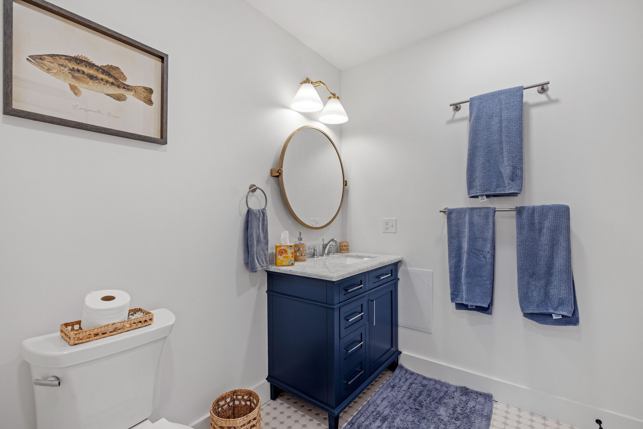Bathroom with a navy vanity, round mirror, and blue towels