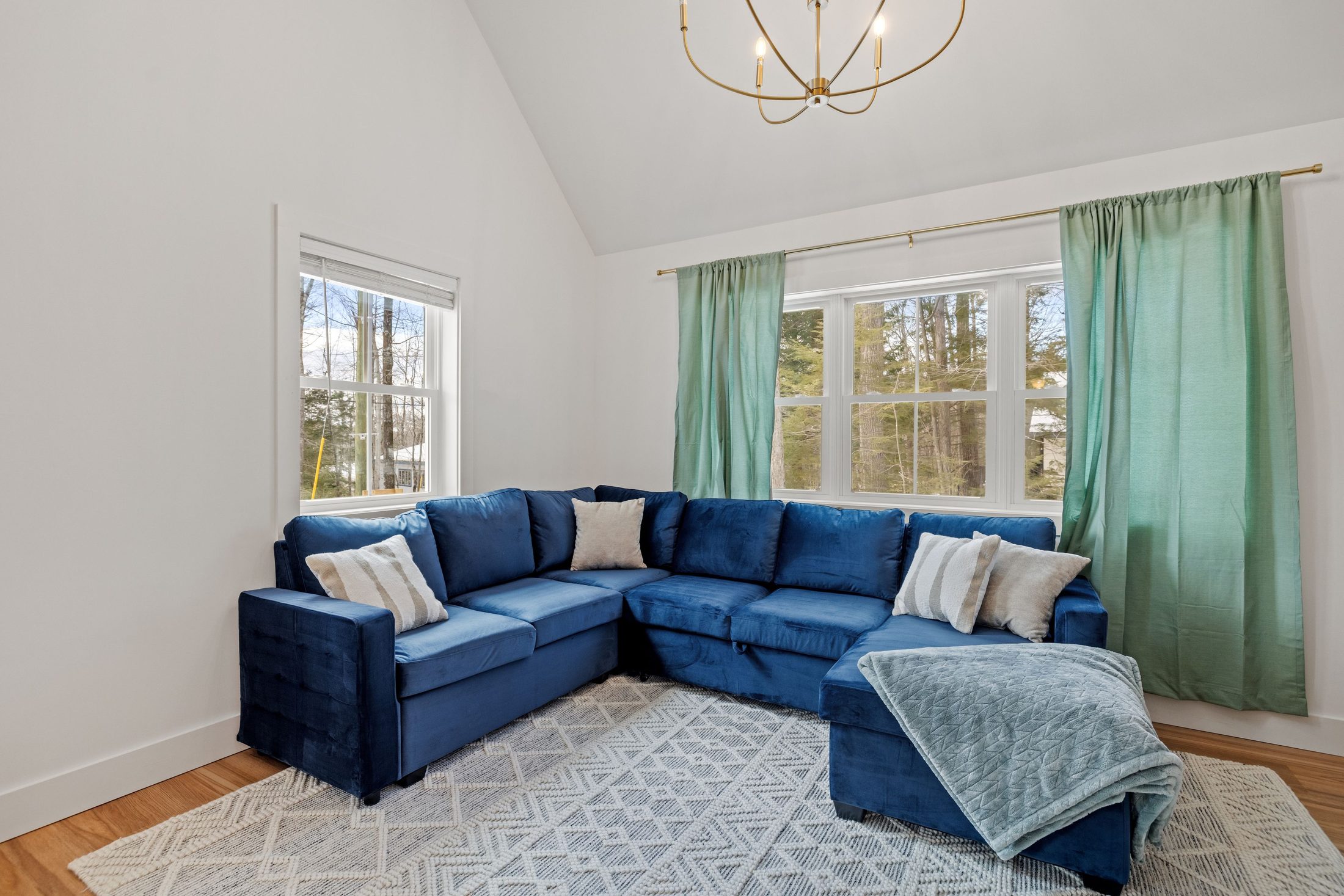 Living room with a blue sectional sofa and green curtains