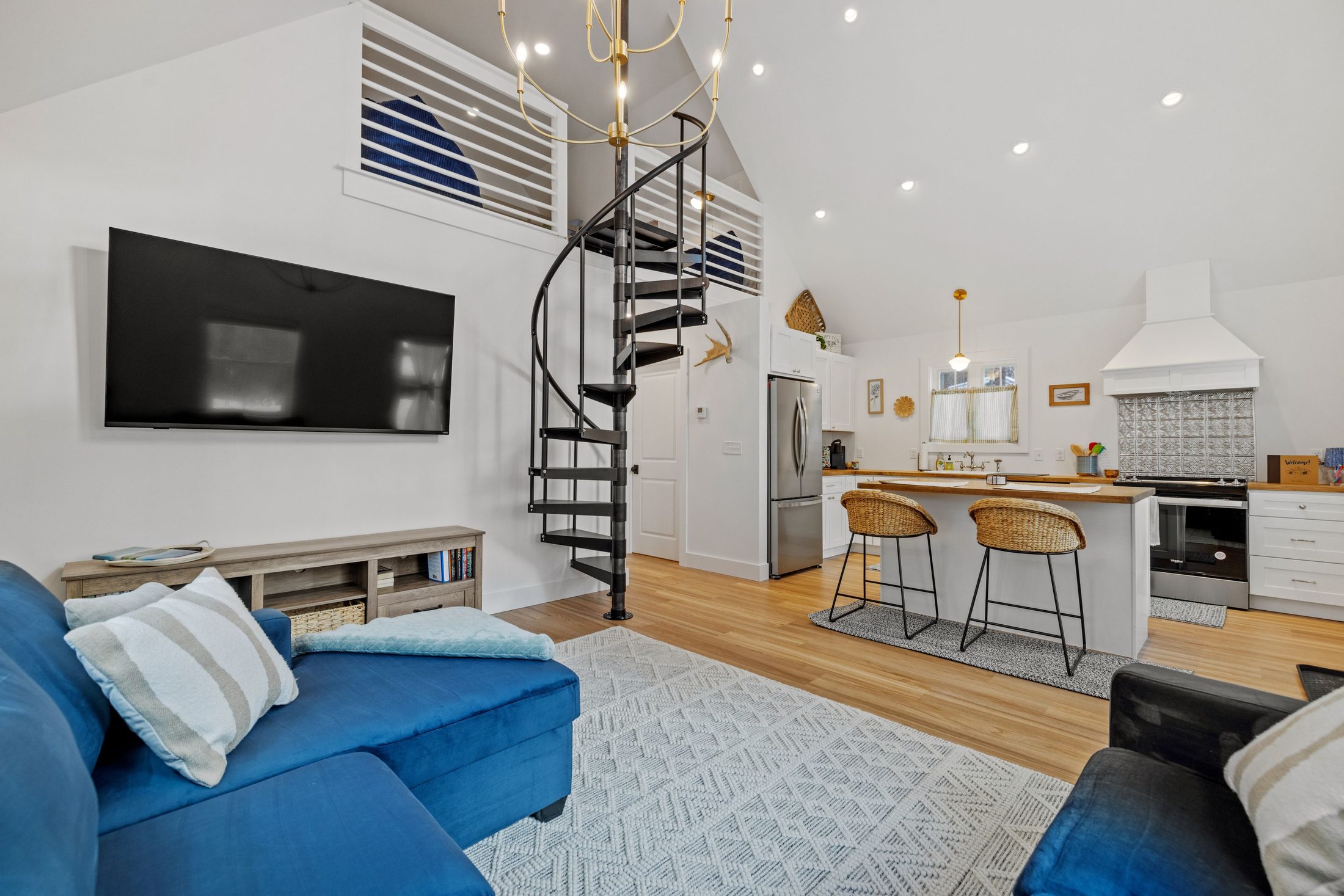 Open-plan living area with a black spiral staircase to the loft, kitchen visible beyond