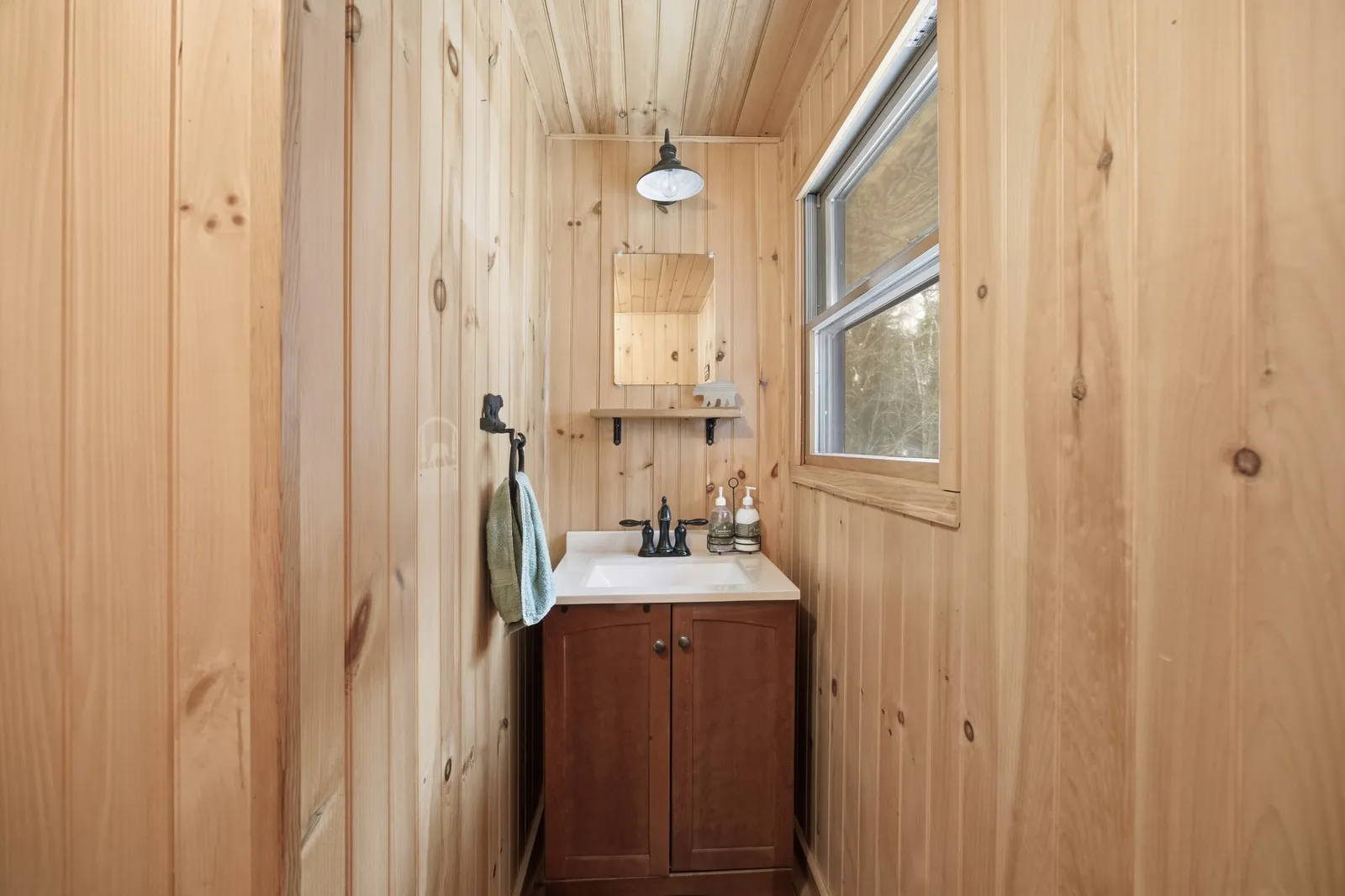 Narrow wood-paneled bathroom with a pedestal-style vanity