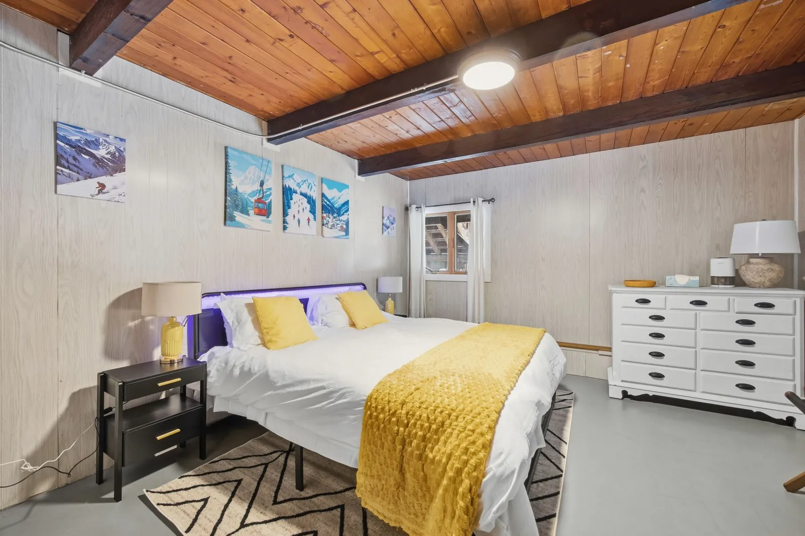 Bedroom with a king bed, wood beam ceiling, and framed ski-themed art
