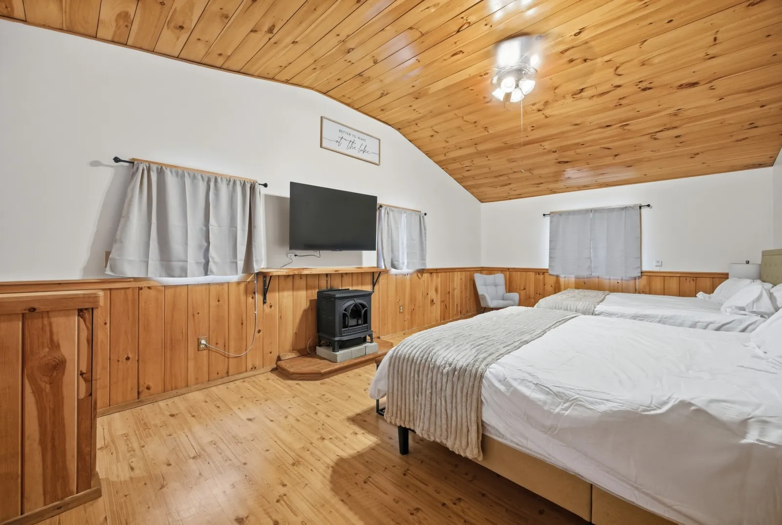 Bedroom with two beds, wood-paneled walls, and a vaulted wood ceiling